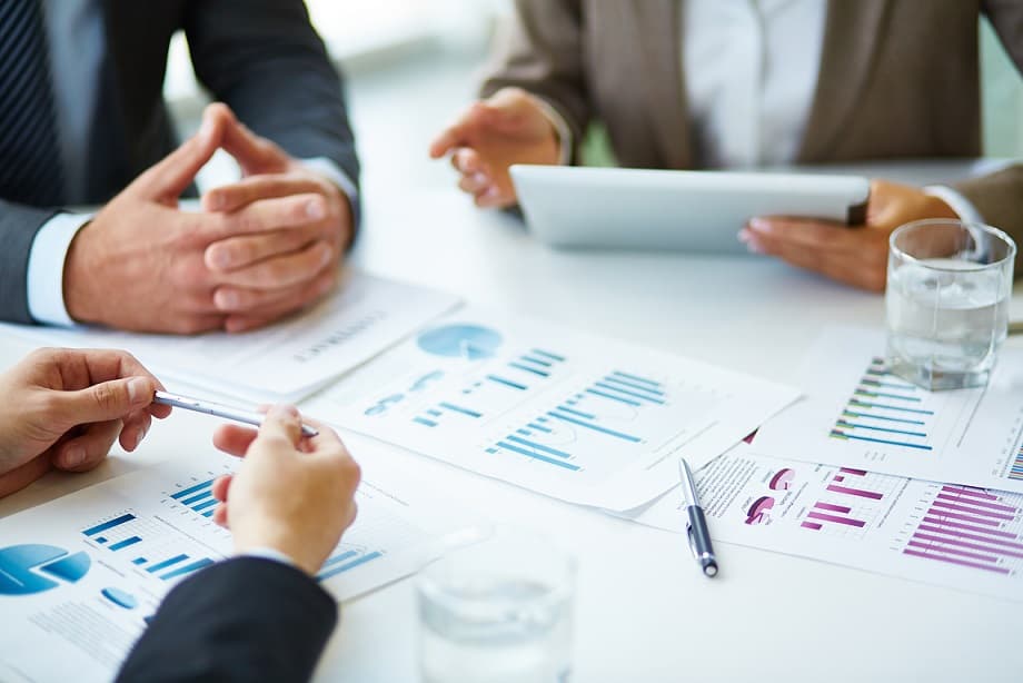 Equipo de consultores analizando gráficos y reportes en una reunión, representando los resultados positivos de una consultoría profesional